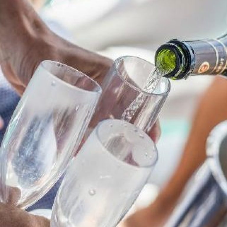 destination wedding pouring champagne on a private yacht tour for weddings in riviera maya, mexico